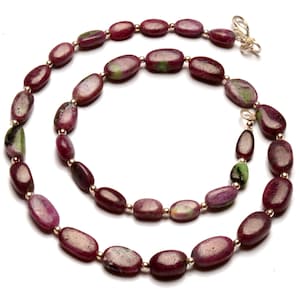 May include: A long necklace made of oval-shaped, pink and green gemstone beads with gold accents.