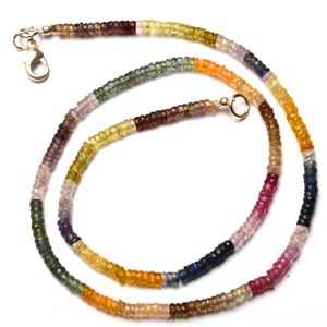 Puede incluir: Un collar de piedras preciosas multicolores con un cierre plateado y un conector dorado. El collar est&aacute; hecho de peque&ntilde;as cuentas redondas en tonos de azul, verde, amarillo, naranja, rojo y marr&oacute;n.