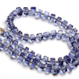 Puede incluir: Un collar de doble cadena hecho de cuentas de amatista facetadas de forma cuadrada separadas por pequeñas cuentas doradas.