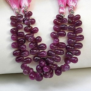 May include: A strand of deep purple gemstone beads in a teardrop shape. The beads are strung on a cord and are ready to be used for jewelry making.