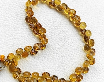 Könnte beinhalten: Eine Kette aus goldbraunen facettierten Edelsteinperlen. Die Perlen sind rund und haben eine glatte, polierte Oberfläche.