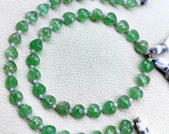 May include: A strand of green gemstone beads in a heart shape. The beads are strung on a white cord and have a tassel at each end.