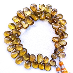 May include: A strand of golden brown teardrop-shaped gemstone beads with a tassel at each end.