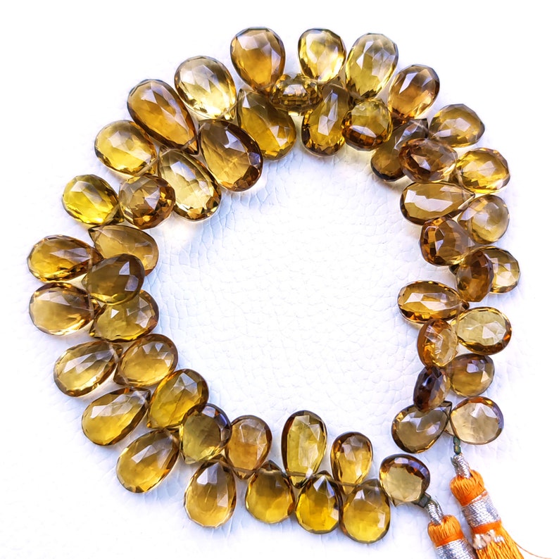 May include: A strand of golden brown teardrop-shaped gemstone beads with a tassel at each end.