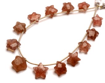 May include: A strand of star-shaped beads made of red sunstone. The beads are strung on a gold wire.