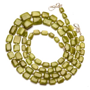 Op de afbeelding: Een lange groene edelsteenketting met rechthoekige kralen. De ketting is gemaakt van twee strengen kralen, en de kralen zijn verbonden door zilverkleurig metaal.
