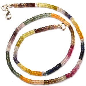 Puede incluir: Un collar de piedras preciosas multicolores con un cierre de plata y una cadena de oro. El collar est&aacute; hecho de peque&ntilde;as piedras preciosas facetadas en tonos de azul, verde, amarillo, naranja, rojo y morado.