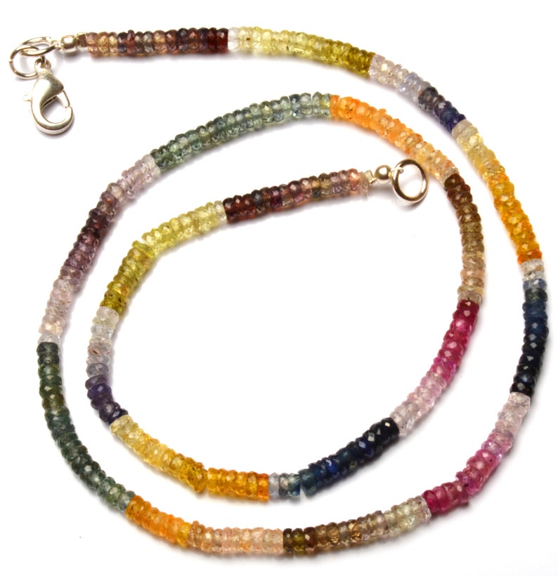 Puede incluir: Un collar de piedras preciosas multicolores con un cierre de plata y una cadena de oro. El collar est&aacute; hecho de peque&ntilde;as piedras preciosas facetadas en tonos de azul, verde, amarillo, naranja, rojo y morado.