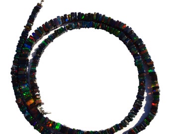 May include: A black opal necklace with a silver clasp. The necklace is made of square-shaped beads that are iridescent and have a variety of colors, including green, blue, red, and gold.