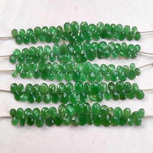 Peut inclure: Un brin de perles de pierres précieuses vertes, chaque perle est facetée et a une forme de larme. Les perles sont enfilées sur un fil et sont prêtes à être utilisées pour la fabrication de bijoux.