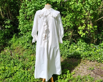 May include: A white cotton nightgown with a ruffled collar and long sleeves. The gown is gathered at the waist and has a flowing skirt.