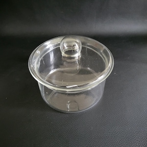 May include: A clear glass jar with a lid. The lid has a small knob on top.
