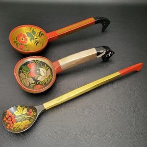 Peut inclure: Trois cuillères en bois avec des motifs floraux peints. Les cuillères ont des accents dorés, rouges et noirs. Les cuillères présentent des baies rouges, des fleurs et des feuilles. Les manches sont peints en or et en rouge.