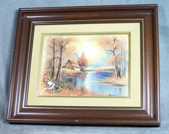 Cuadro esmaltado vintage de una casa junto al agua, marco de madera, paspartú de terciopelo beige.
