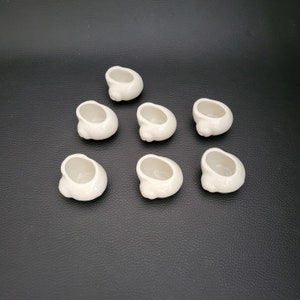 Op de afbeelding: Zeven kleine witte keramische bekers of kommen, mogelijk voor vetplanten of andere kleine planten.