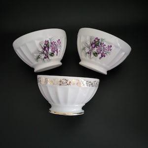 Peut inclure: Trois bols en céramique blanche avec des motifs floraux. Les bols ont un bord cannelé et une bordure dorée autour du haut.