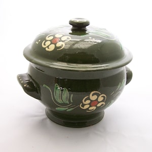 Könnte beinhalten: Ein grüner Keramiktopf mit Deckel, verziert mit handgemalten Blumendesigns in Gelb, Rot und Grün. Der Topf hat zwei Griffe und einen runden Körper.
