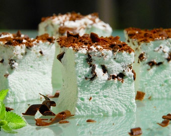 May include: Close-up of four green and white mint-flavored marshmallows topped with chocolate shavings.