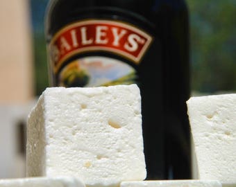 May include: A bottle of Baileys Irish Cream liqueur with a white label and red lettering. The bottle is in front of two white marshmallows.
