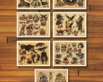 May include: Collection of vintage-style tattoo flash art prints. Each print features classic tattoo designs, including geishas, snakes, eagles, panthers, and pin-up girls. The prints are displayed on a wooden background, showcasing the traditional tattoo aesthetic.