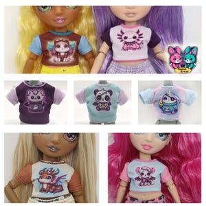 K&ouml;nnte beinhalten: Eine Sammlung von Puppen-T-Shirts mit verschiedenen Cartoon-Tierdesigns. Die Shirts haben kurze &Auml;rmel und sind in Farben wie Braun, Lila, Blau und Rosa gehalten. Einige Shirts zeigen Bilder eines gefl&uuml;gelten Wesens, eines Axolotls, einer Katze, eines Pandas und eines Drachen.