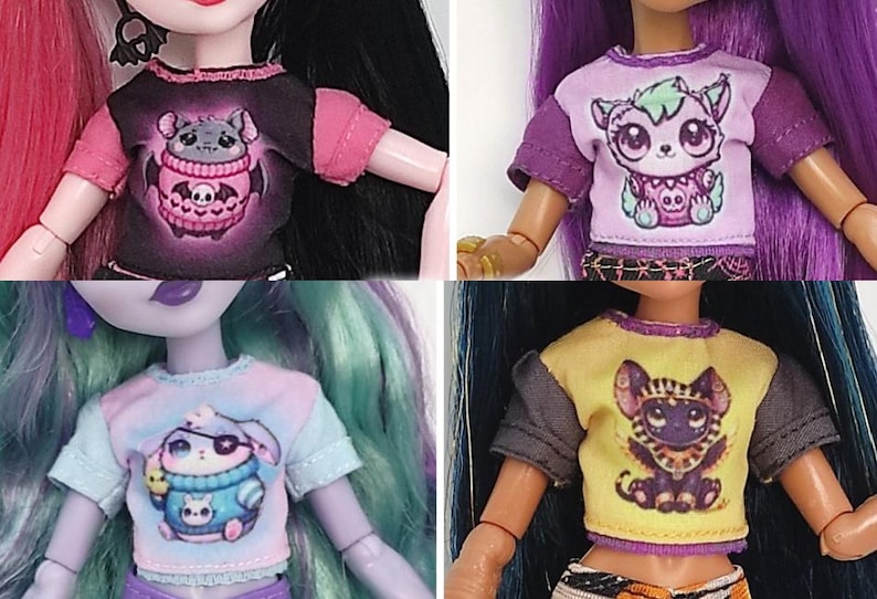 K&ouml;nnte beinhalten: Vier Puppenoberteile mit kurzen &Auml;rmeln. Jedes Shirt zeigt ein anderes Cartoon-Kreaturen-Design. Die Shirts haben verschiedene Farbkombinationen, darunter Schwarz und Rosa, Lila und Wei&szlig;, Blau und Pastell sowie Gelb und Grau. Die Oberteile sind Teil eines Puppenkleidungssets.