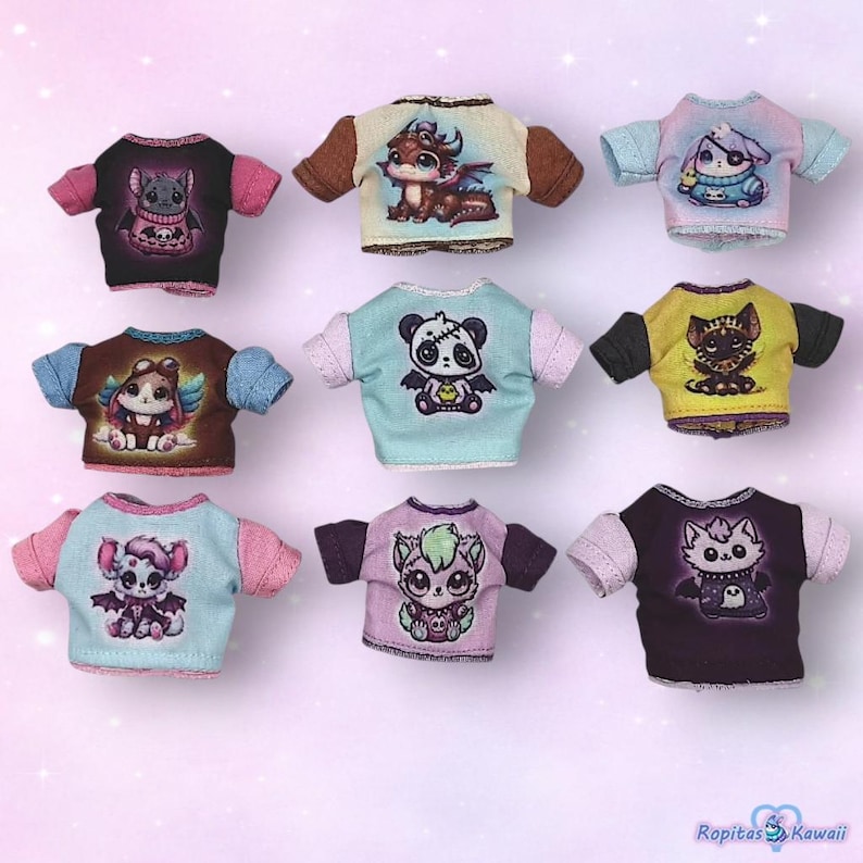 K&ouml;nnte beinhalten: Neun Miniatur-T-Shirts mit verschiedenen Cartoon-Kreaturen-Designs. Jedes Shirt hat kurze &Auml;rmel in Kontrastfarben wie Rosa, Blau, Braun und Schwarz. Die Designs umfassen einen Drachen, einen Panda, eine Katze und andere niedliche Charaktere.