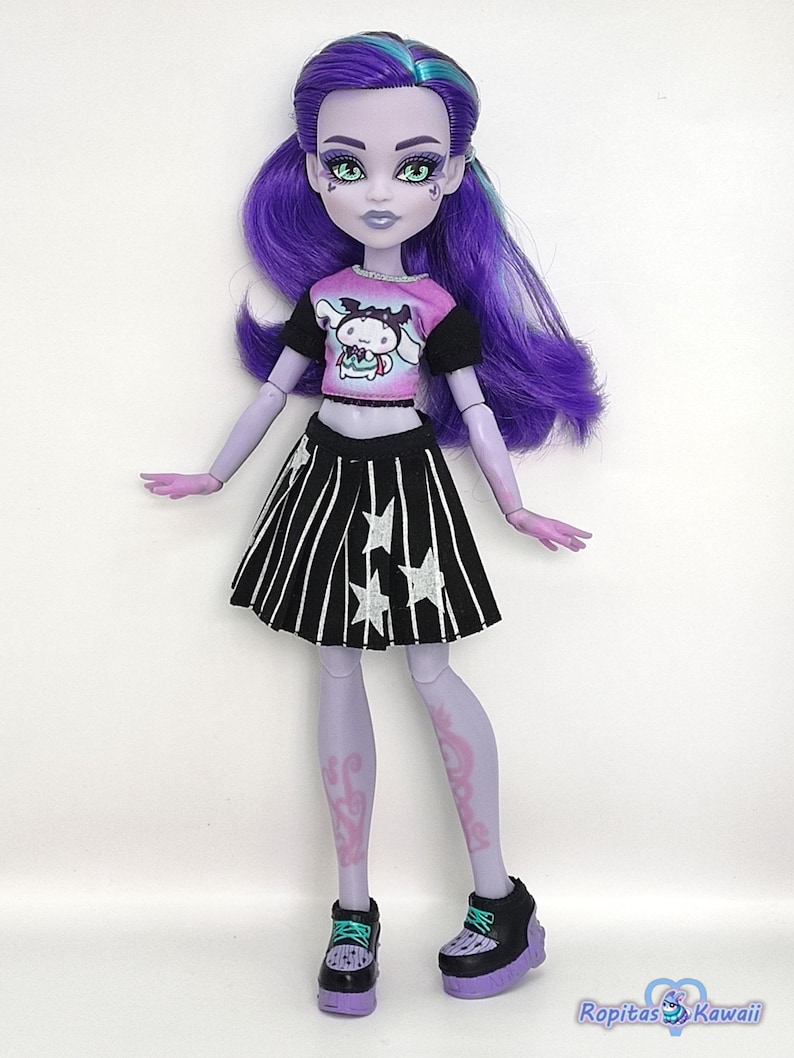 K&ouml;nnte beinhalten: Puppe mit violetter Haut, Haaren und Augen, tr&auml;gt ein rosa-schwarzes Oberteil mit einer Cartoonfigur, einen schwarz-wei&szlig; gestreiften Rock mit Sternen und schwarze Plateauschuhe. Die Puppe hat ein einzigartiges, stilisiertes Aussehen.