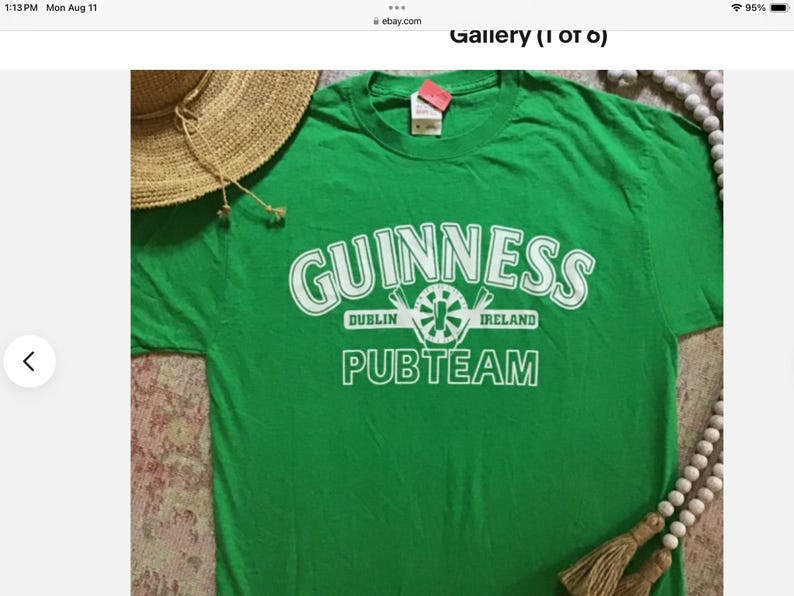 May include: Green t-shirt with the Guinness logo in white, including the words "Dublin Ireland" and "Pubteam". A straw hat and beaded necklace with tassels are partially visible in the image.
