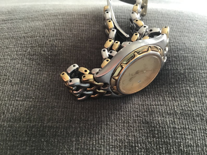 May include: A two-tone gold and silver wristwatch with a round face and a metal band.