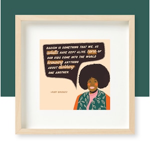 Könnte beinhalten: Ein gerahmter Druck mit einem Zitat von Ruby Bridges: "Rassismus ist etwas, das wir, als Erwachsene, am Leben erhalten haben. Keines unserer Kinder kommt in die Welt und weiß etwas darüber, andere nicht zu mögen." Das Zitat befindet sich in einer Sprechblase über einer Illustration von Ruby Bridges mit Afro-Frisur.