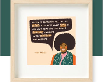 May include: A framed print featuring a quote by Ruby Bridges: "Racism is something that we, as adults have kept alive. None of our kids come into the world knowing anything about disliking one another." The quote is in a speech bubble above an illustration of Ruby Bridges with an afro.