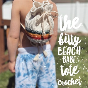 May include: A white crocheted tote bag with colorful stripes, worn as a backpack by a child. The text "the bitty beach babe tote crochet pattern" is superimposed on the image.