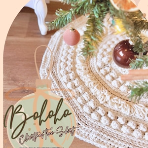 Może przedstawiać: Kremowa, szydełkowa spódnica na choinkę z teksturowanym wzorem ściegu bobble. Spódnica jest okrągła i otacza udekorowaną choinkę z ozdobami. Obraz zawiera tekst "Bololo Christmas Tree Skirt" i "PDF Crochet Pattern".