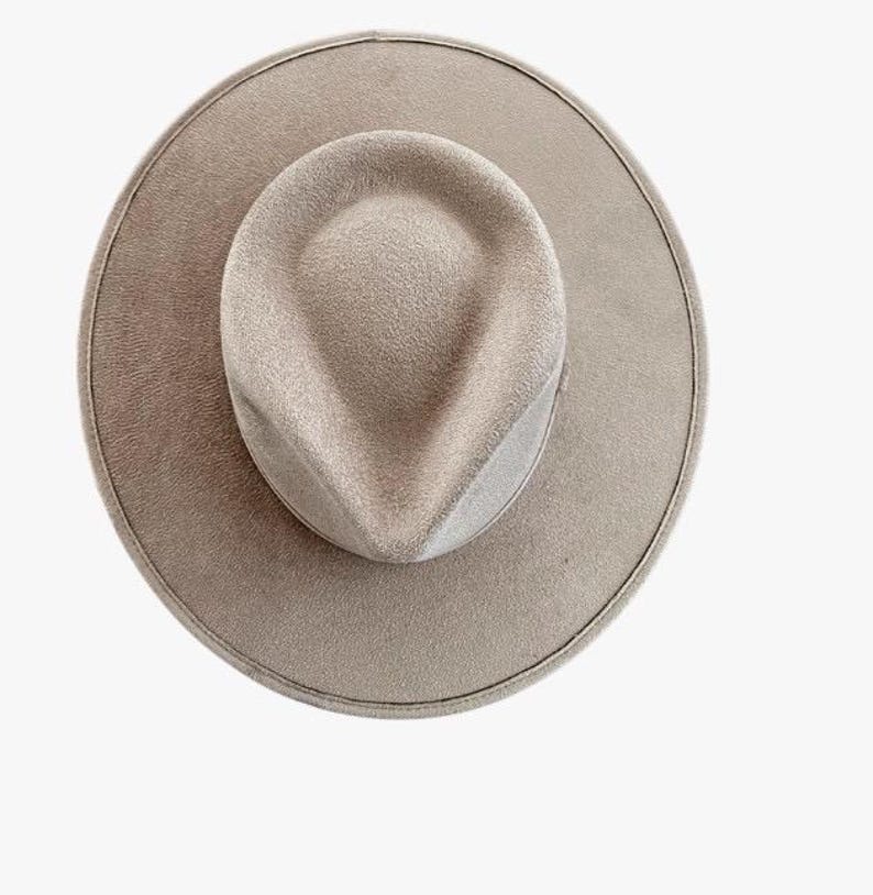Pu&ograve; includere: Un cappello fedora a tesa larga di colore tortora uniforme, caratterizzato da una rientranza a goccia sulla corona e da una tesa piatta e strutturata. La superficie del cappello presenta una consistenza uniforme simile al feltro, vista dall'alto.