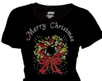 May include: Black t-shirt with a red and green Christmas wreath design featuring a red bow and the words "Merry Christmas" in rhinestones.