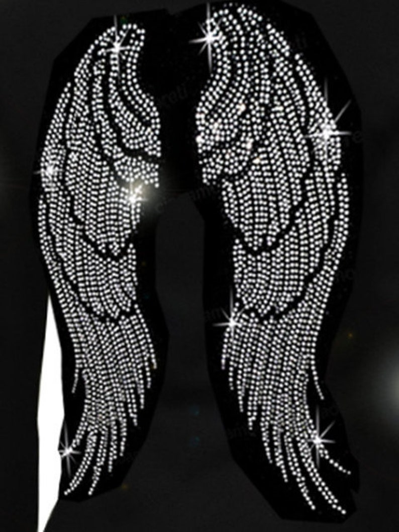 May include: A black garment with a pair of large angel wings made of rhinestones. The wings are detailed with rows of sparkling crystals.