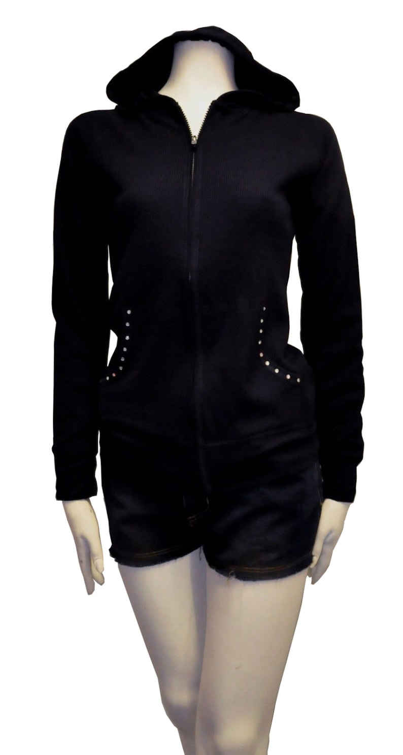 May include: Black zip-up hoodie with a hood and long sleeves. The hoodie has a ribbed texture and silver studs on the sides.