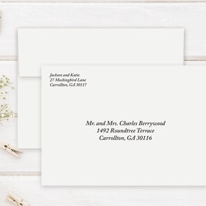 May include: Two off-white envelopes with black text. One envelope has the address "Jackson and Katie, 27 Mockingbird Lane, Carrollton, GA 30117." The other envelope has the address "Mr. and Mrs. Charles Berrywood, 1492 Roundtree Terrace, Carrollton, GA 30116."