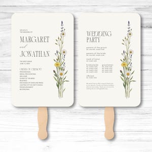 May include: Two rectangular wedding program fans with rounded corners and wooden handles. The white cards feature black text and a vertical illustration of wildflowers including daisies and lavender. The text details the wedding ceremony order.