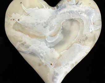 Puede incluir: Una escultura de cerámica en forma de corazón con un diseño marmoleado blanco y gris y detalles dorados.