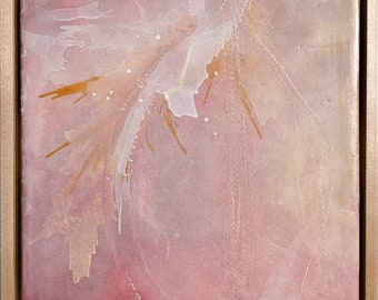 Puede incluir: Pintura abstracta cuadrada enmarcada en madera clara. La obra presenta un fondo rosa suave con detalles blancos y dorados. El diseño incluye formas fluidas y salpicaduras, creando una sensación delicada y etérea.
