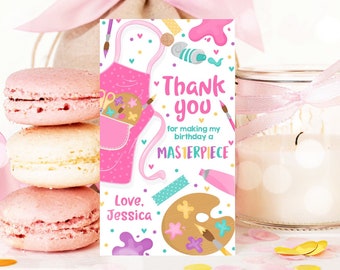 May include: Pink and white thank you tag with a pink art smock, paintbrushes, paint tubes, and a paint palette. The text reads "Thank you for making my birthday a Masterpiece. Love, Jessica."