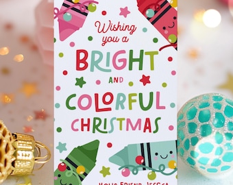 May include: A white Christmas gift tag with the message "Wishing you a Bright and Colorful Christmas." The tag features cartoon crayons and stars in pink, green, and red. The tag is personalized with the name "Jessica".