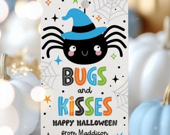 Può includere: Un'etichetta bianca con un ragno nero che indossa un cappello da strega blu. L'etichetta ha un testo colorato che dice "Bugs and Kisses Happy Halloween from Maddison".