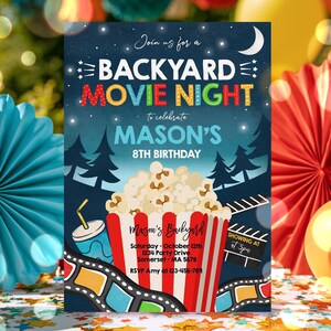 May include: A rectangular invitation card for a backyard movie night birthday party. The dark blue background features a crescent moon, stars, and silhouettes of pine trees. A red and white striped popcorn bucket is centered with text.