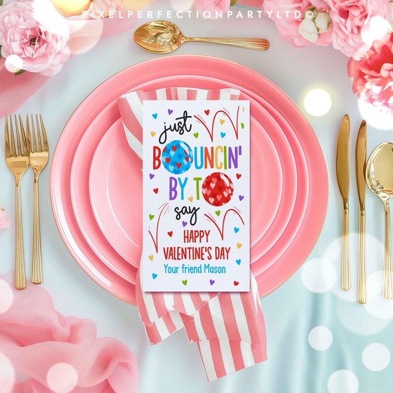 May include: A pink and white striped napkin with a white card on top. The card has a colorful illustration of bouncing balls and the text "Just Bouncing By To Say Happy Valentine's Day Your friend Mason".