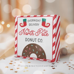 May include: A festive box with red and white diagonal stripes and the text "Overnight Delivery North Pole Donut Co." The box features a graphic of a chocolate donut with sprinkles and elf shoes. The box is on a white surface with gold star confetti.