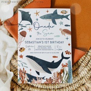 May include: A white invitation card with a blue and brown underwater theme. The text reads "Oneder the Sea" and "Sebastian's 1st Birthday". The invitation includes details for the party, including the date, time, and location.