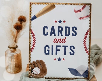 Könnte beinhalten: Ein weißes Schild mit goldenem Rahmen und rot-weiß-blauen Baseball-Grafiken. Das Schild trägt die Aufschrift "Cards and Gifts" mit drei Sternen über dem Wort "Gifts".